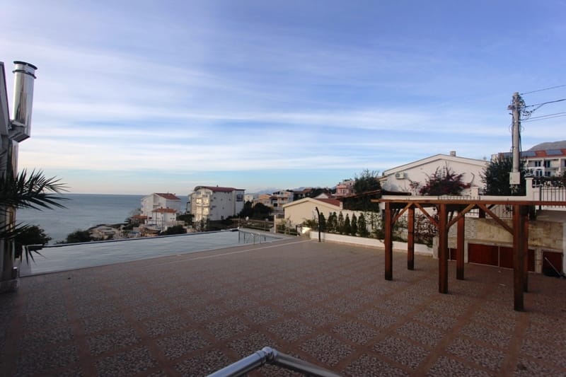 Open terrace with a pool and sea view in a house in Utjeha, Montenegro: tiled flooring and a wooden canopy.