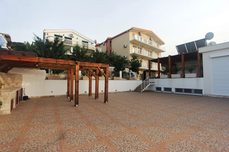 Spacious terrace with a wooden pergola and barbecue area by the house in Utjeha, Montenegro. View of the residential complex.