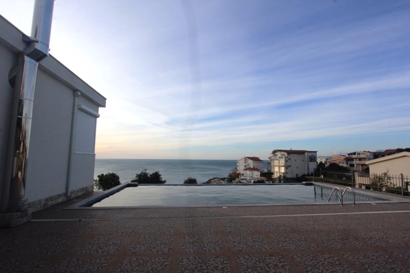 Outdoor pool with panoramic sea view by the house in Utjeha, Montenegro. Tiled terrace and modern architecture.