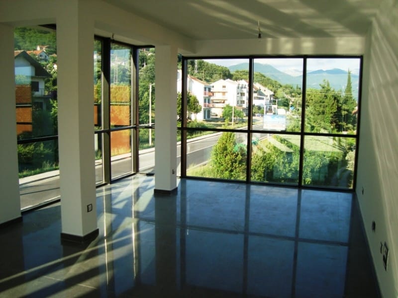 Commercial premises in Baošići, Montenegro: a bright living room with panoramic windows and views of the mountains and the road.