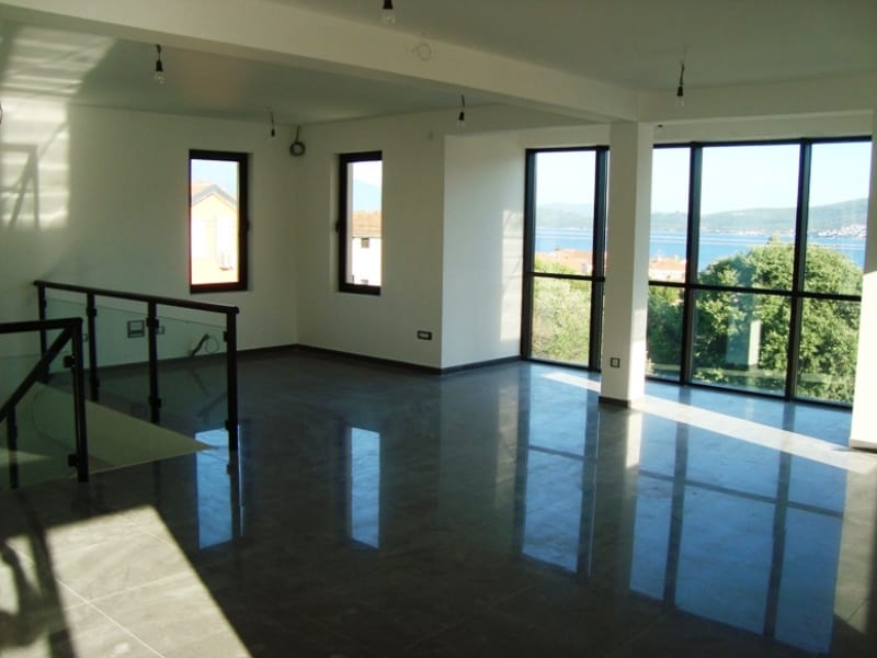 Spacious living room with panoramic windows and sea view in Baošići, Montenegro: light finishes and tiled floor.