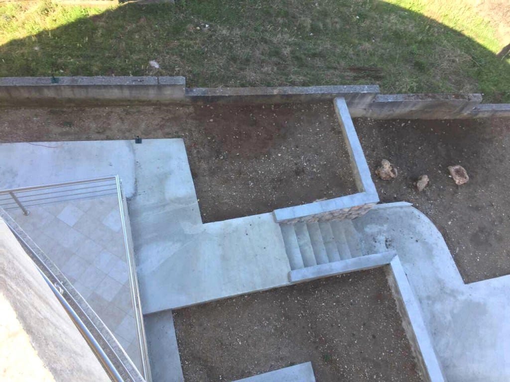 Top view of the terrace and landscaped grounds of a villa in Utjeha, Montenegro: concrete paths and stairs.