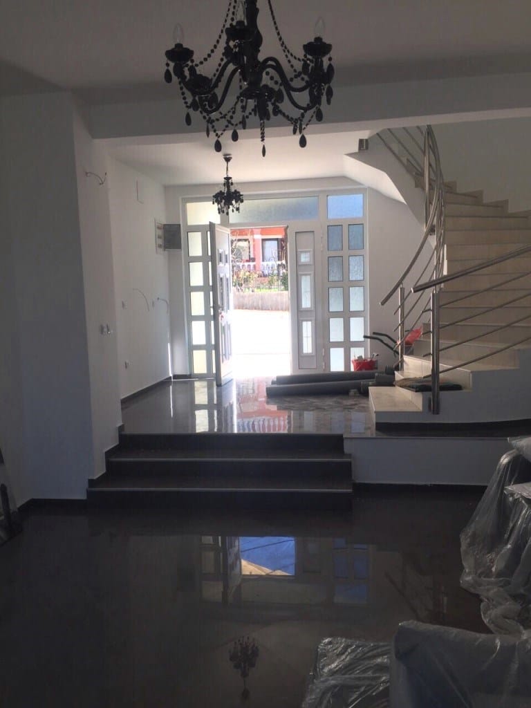 Living room interior with staircase and chandelier in a villa in Uteha, Montenegro: a bright hall with a glossy floor and entrance.