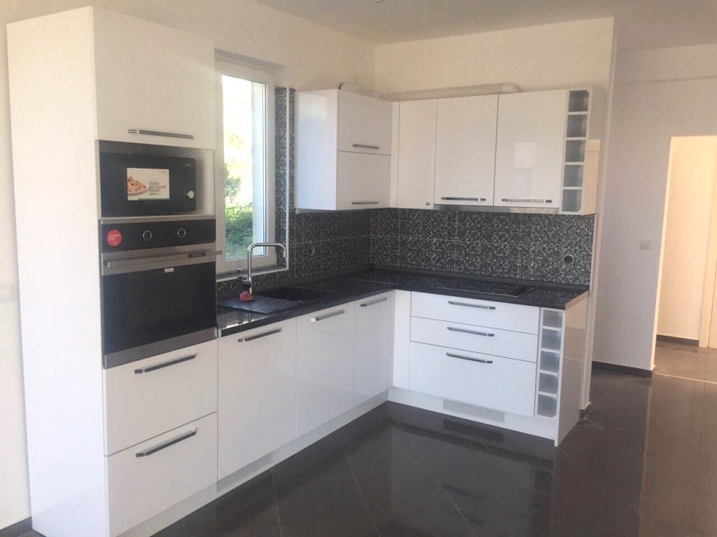 Modern white kitchen with glossy fronts and a dark countertop in a villa in Utjeha, Montenegro.