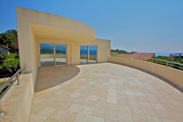 Spacious villa terrace in Utjeha, Montenegro, with panoramic sea views, light finishes, and glass doors.