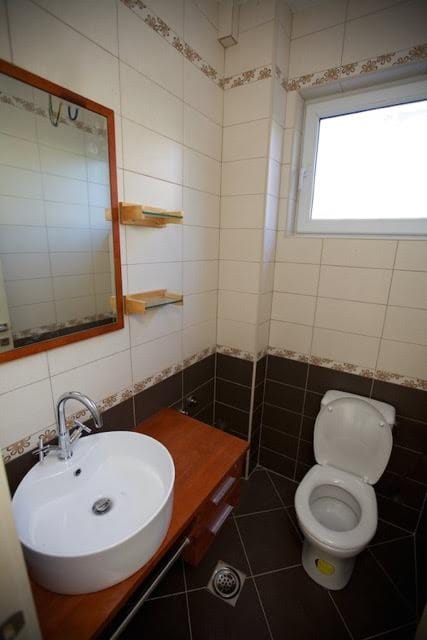 Bright bathroom with ceramic tiles and a wooden vanity in a villa in Utjeha, Montenegro.