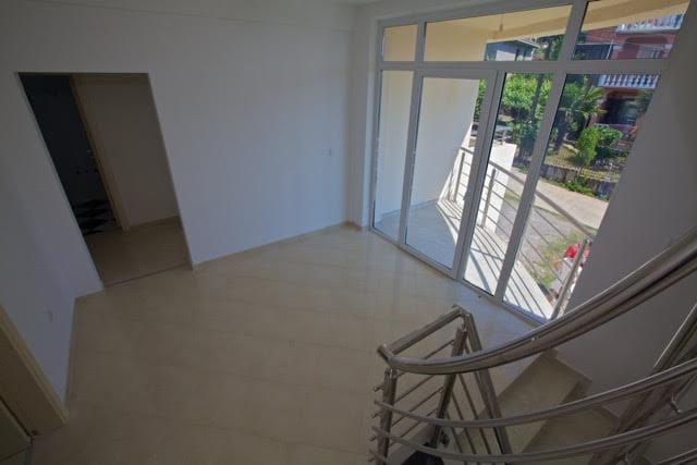 Bright living room with panoramic windows and staircase in a villa in Utjeha, Montenegro: modern finishes and garden view.