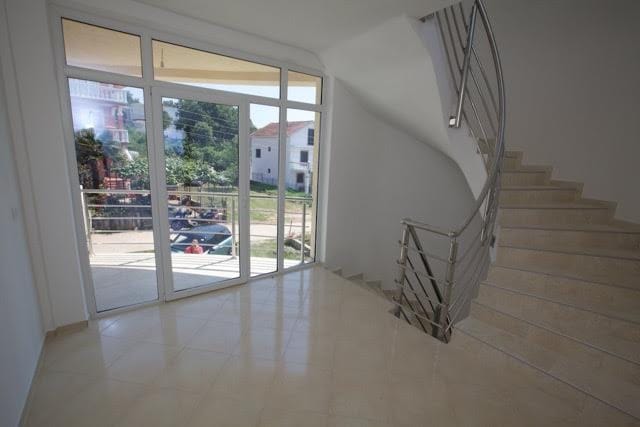 Bright living room with panoramic windows and a staircase in a villa in Utjeha, Montenegro: modern interior and garden view.