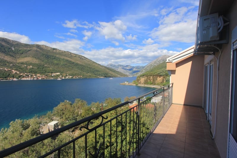 Villa balcony in Lepetane, Montenegro, with panoramic views of Kotor Bay and the mountains, and tiled flooring.
