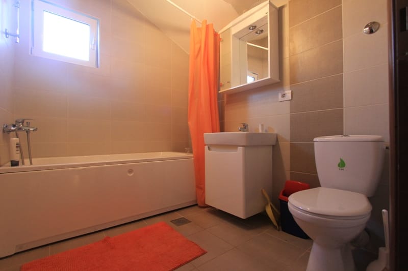 Bathroom with white fixtures and tile in a villa in Lepetani, Montenegro: bathtub, sink, and toilet.