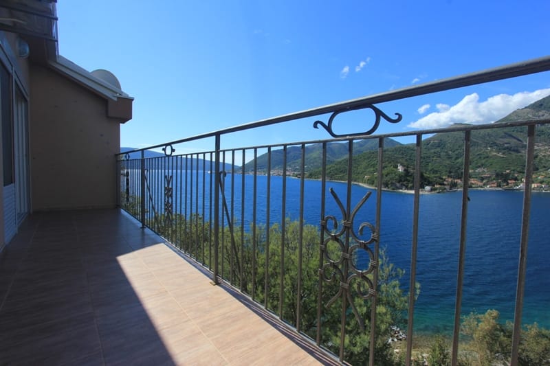 Balcony of a villa in Lepetani, Montenegro, with wrought-iron railing and panoramic views of the sea and the mountains of the Bay of Kotor.