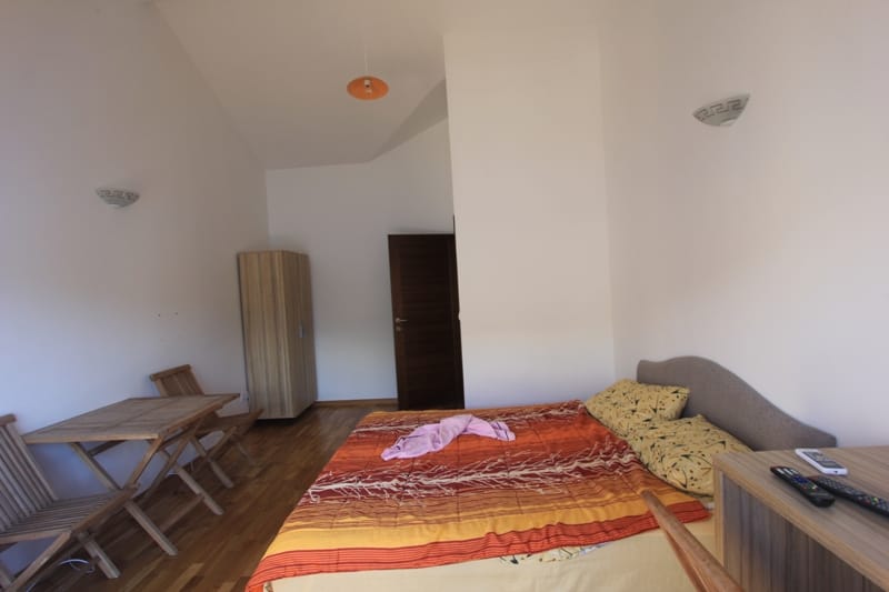 Bedroom in a villa in Lepetani, Montenegro: double bed, wooden table with chairs and wardrobe, parquet floor.