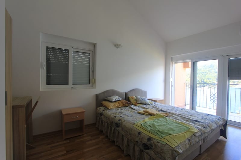 Bedroom with a double bed and access to a balcony with sea views in a villa in Lepetani, Montenegro.