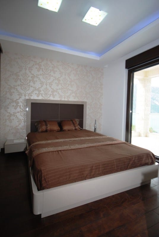 Modern bedroom with a double bed in a residential complex in Kostanica, Montenegro, with access to the terrace and a view.