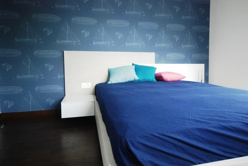 Bedroom in a residential complex in Kostanica, Montenegro: a double bed, blue wallpaper with a nautical print, and dark flooring.