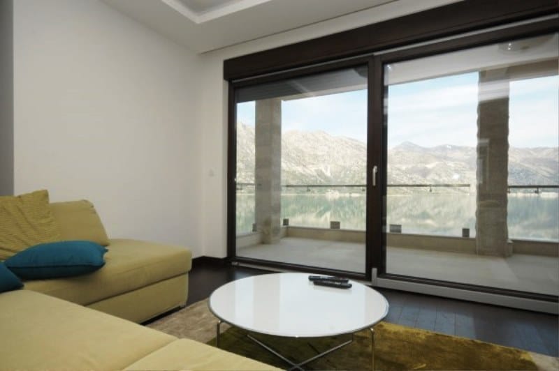 Living room with panoramic sea and mountain views in Kostanica residential complex, Montenegro: modern furniture and terrace.