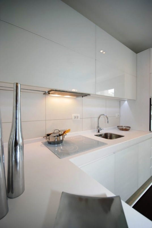 Modern white kitchen with glossy fronts in a residential complex, Kostanica, Montenegro: built-in appliances and sink.