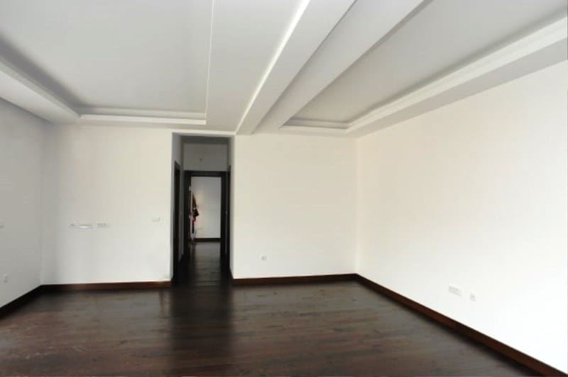 Spacious living room with white walls and dark parquet flooring in a residential complex, Kostanica, Montenegro.