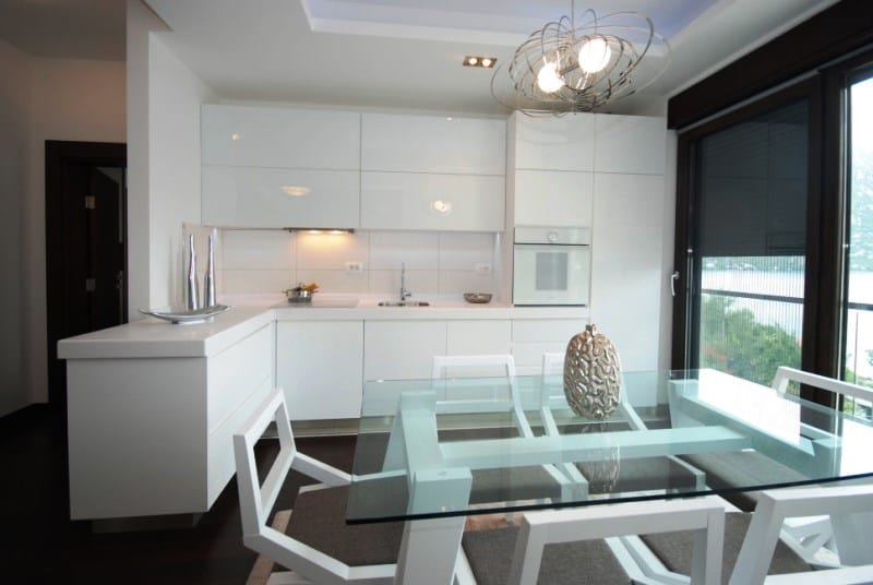 Modern white kitchen with a glass table in a residential complex, Kostanica, Montenegro: sea view and stylish interior.