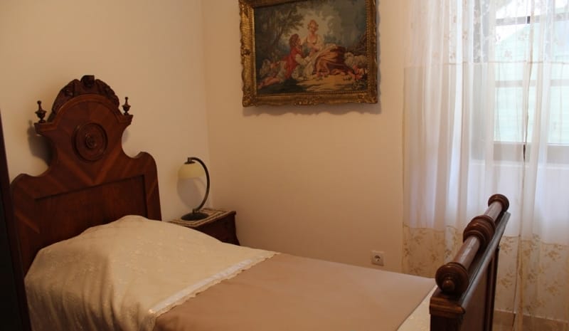 Bedroom with an antique wooden bed and a painting in a house for sale in Strp, Montenegro.