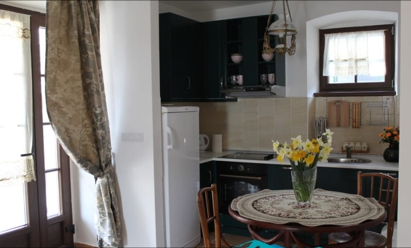 Cozy kitchen with dark cabinetry and a dining area in a house, Strp, Montenegro. Interior with a vintage chandelier.