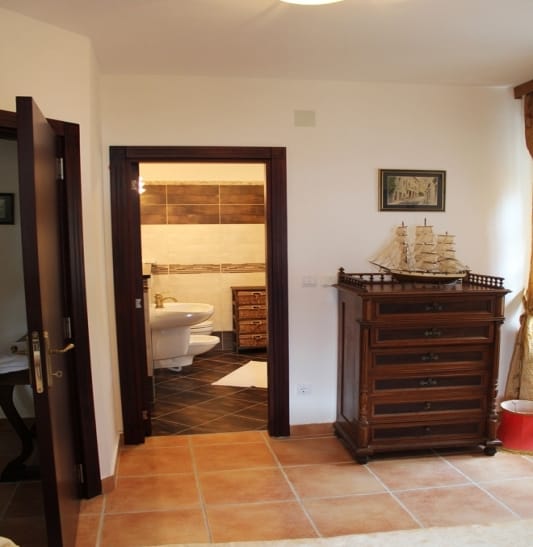 Bedroom with a wooden dresser and a view of the bathroom in a house for sale, Strp, Montenegro.