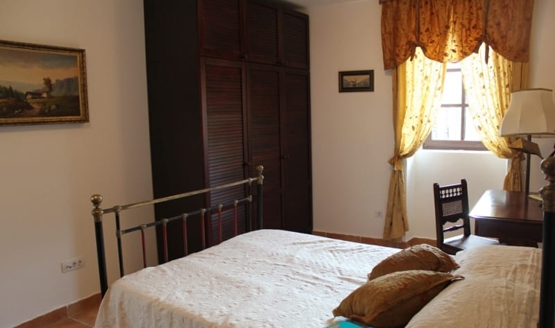 Cozy bedroom with a bed and a wooden wardrobe in a house in Strp, Montenegro. Classic interior with paintings.
