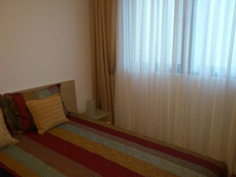 Cozy bedroom with a double bed in an apartment in Pržno, Montenegro: light finishes and blackout curtains on the windows.