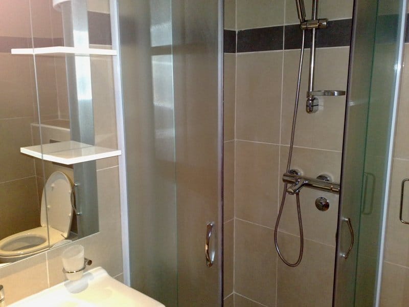 Modern bathroom with a shower cabin and light-colored tiles in an apartment for sale in Pržno, Montenegro.