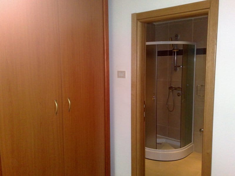 Built-in wooden wardrobe and entrance to the bathroom with a shower cabin in an apartment, Pržno, Montenegro.