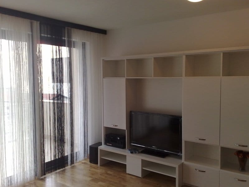 Living room with white furniture and access to the balcony in an apartment in Pržno, Montenegro. Modern interior with a TV area.