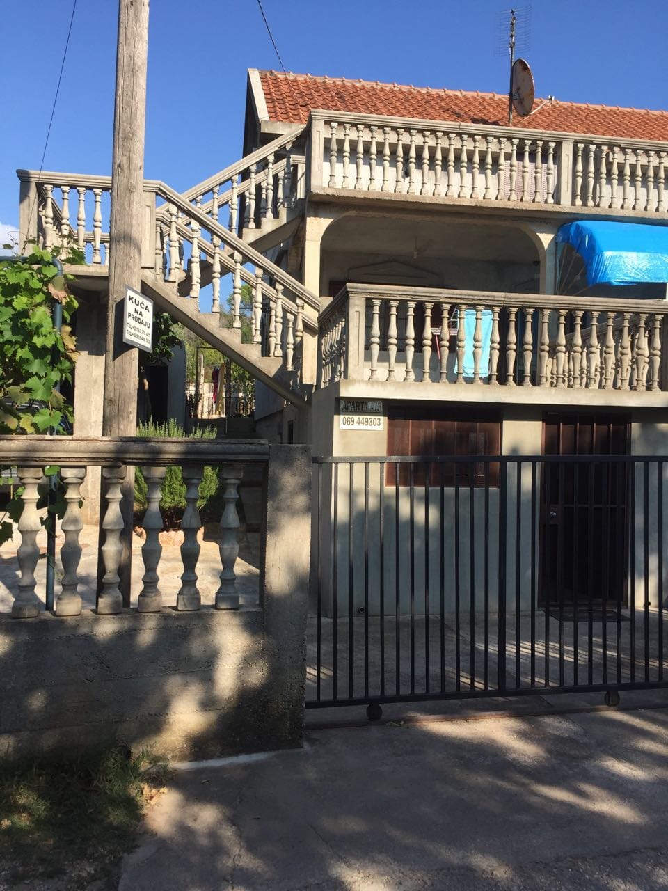 Two-story house for sale in Krimovica, Montenegro: facade with concrete balustrades, exterior staircase, and gate.