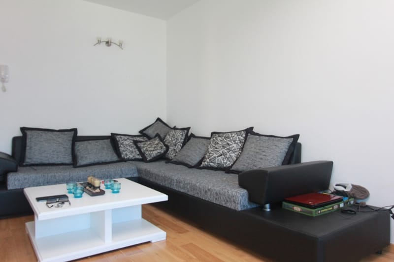 Living room with a corner sofa and a white coffee table in a house, Stoliv, Montenegro. Bright interior with parquet flooring.