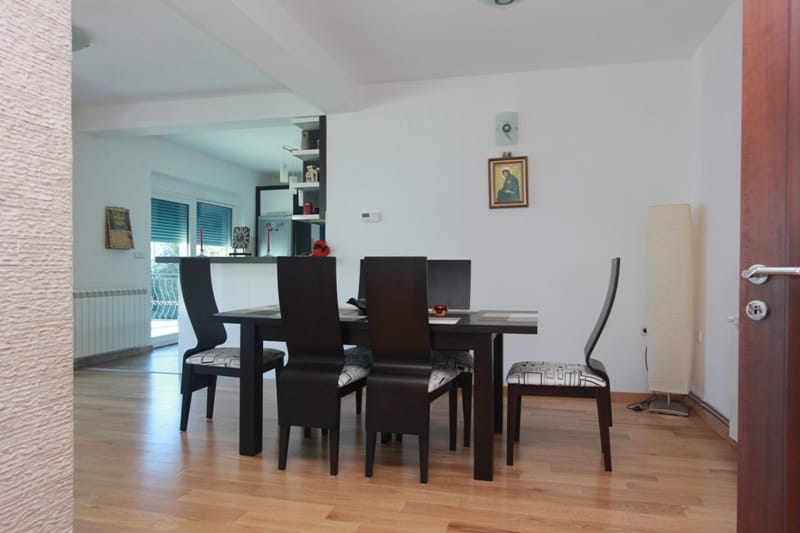 Living room with dining area in a house in Stoliv, Montenegro: dark table, chairs, and light parquet flooring.