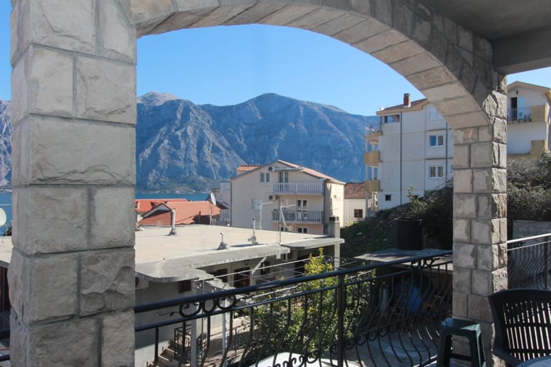 View from the stone terrace of the house in Stoliv, Montenegro, of the mountains and sea: panorama from a balcony with a wrought-iron railing.