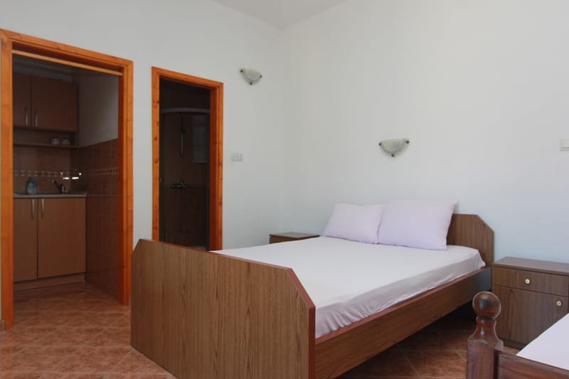 Bright bedroom with a double bed, bedside tables, and access to the kitchen in a house, Stoliv, Montenegro.