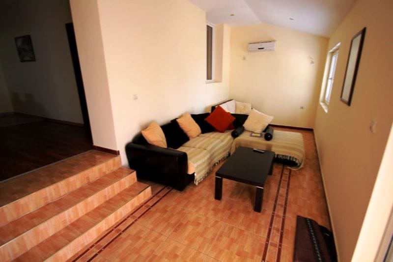 Living room with an L-shaped sofa and coffee table in a house, Đenovići, Montenegro: interior with tile flooring and air conditioning.