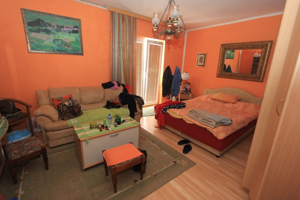 Living room with a double bed and sofa in a house, Radanovići, Montenegro: interior with orange walls and furniture.