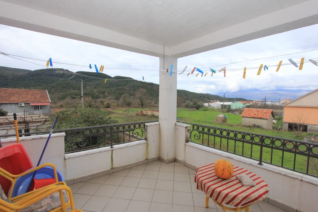 Spacious balcony with mountain views in a house, Radanovici, Montenegro: tiled floor, wrought-iron railing, and a table.