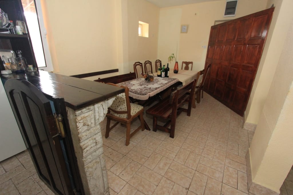 Kitchen-dining room with wooden furniture and a bar counter in a house, Radanovici, Montenegro. Tiled floor, classic style.