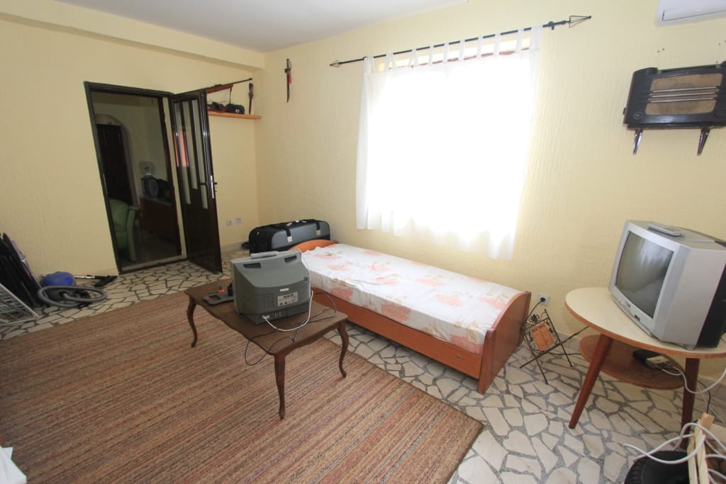 Bedroom in a house in Radanovići, Montenegro: single bed, TV, rug, and tiled floor in the interior.