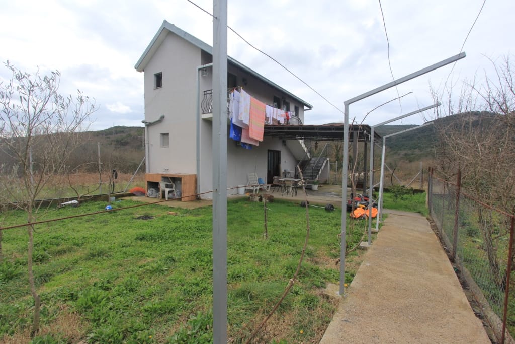 Two-story house with a plot and summer kitchen in Radanovici, Montenegro: view of the facade, garden, and terrace with a canopy.