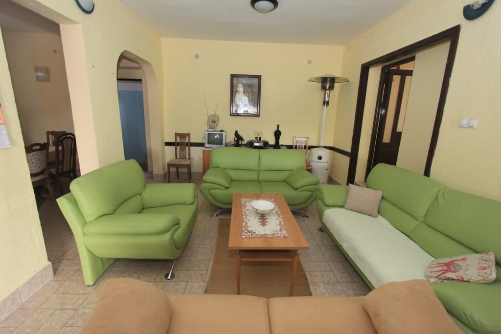 Living room with bright green leather sofas in a house for sale, Radanovići, Montenegro: interior with tiled floor.