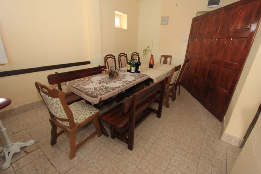 Living room with wooden furniture and a dining table in a house, Radanovici, Montenegro. Interior with tiled flooring.