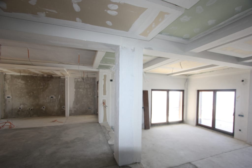 Living room under renovation in a villa in Blizikuće, Montenegro: rough finish, concrete floors, and panoramic windows.