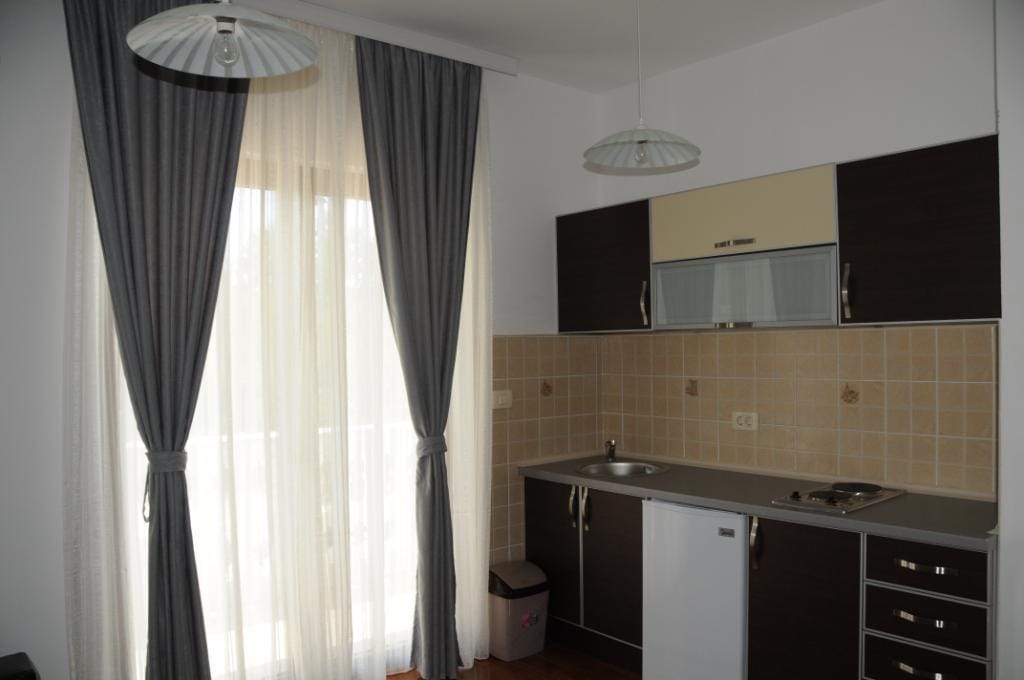 Modern kitchen in villa apartments in Markovichi, Montenegro: dark cabinetry, tile, and access to the balcony.