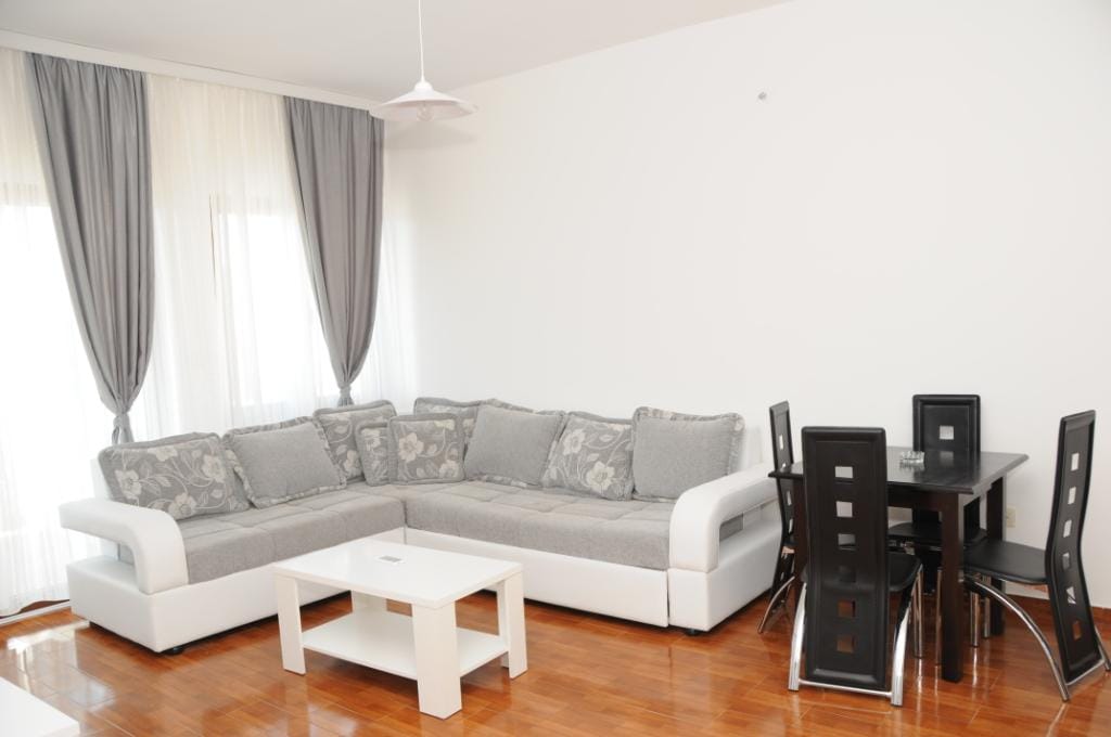 Living room with a corner sofa and dining area in a villa in Markovichi, Montenegro: bright interior, parquet floor.