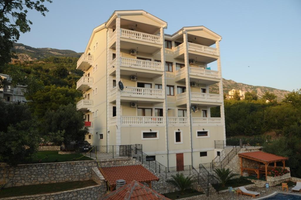 Four-story villa with balconies and a pool in the village of Markovichi, Montenegro: front view and surrounding grounds.