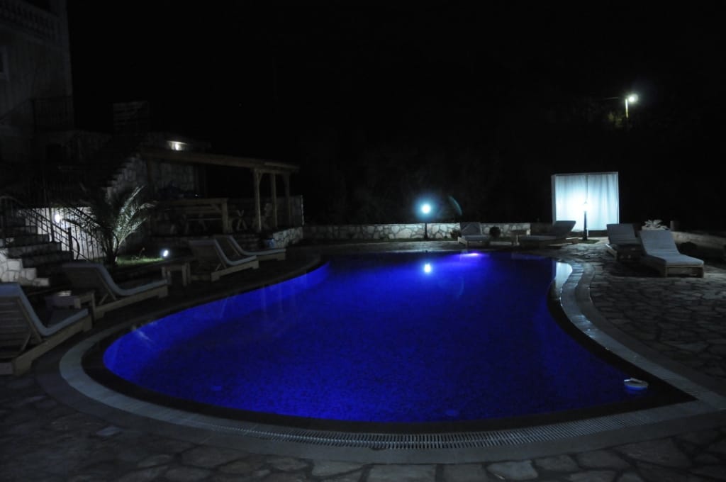 Outdoor pool with night lighting and sun loungers at a villa in Markovichi, Montenegro.