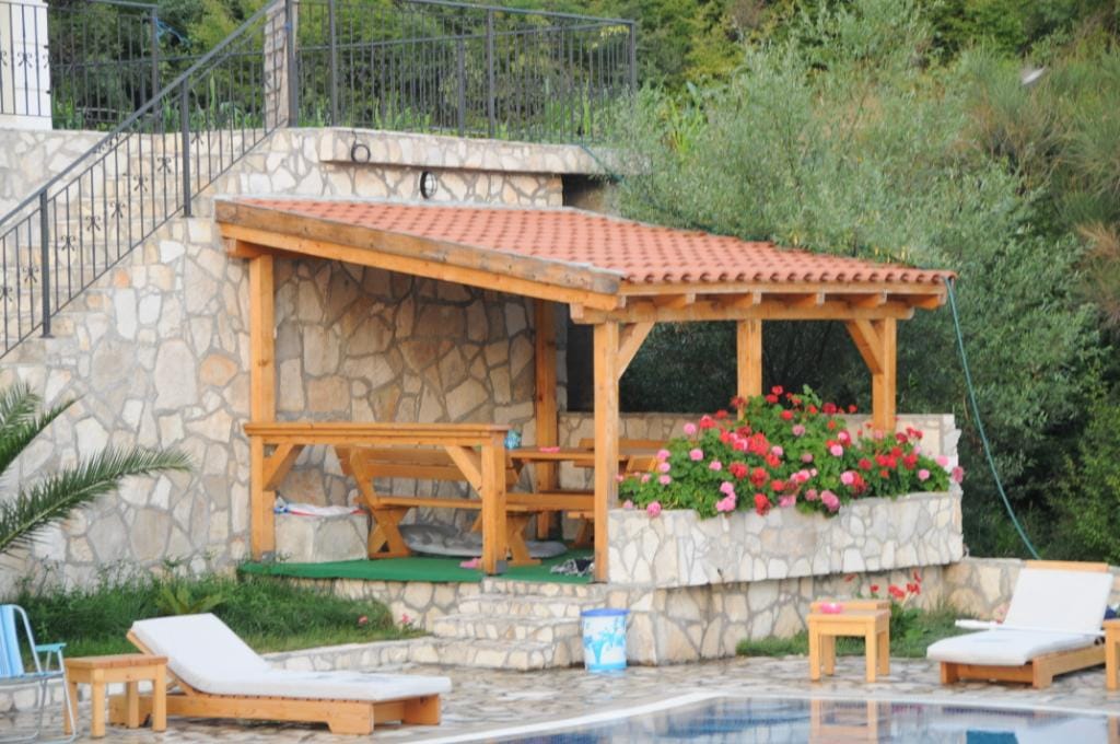 Wooden gazebo by the pool with stone finishes at a villa in Markovichi, Montenegro: a relaxation area with garden furniture.
